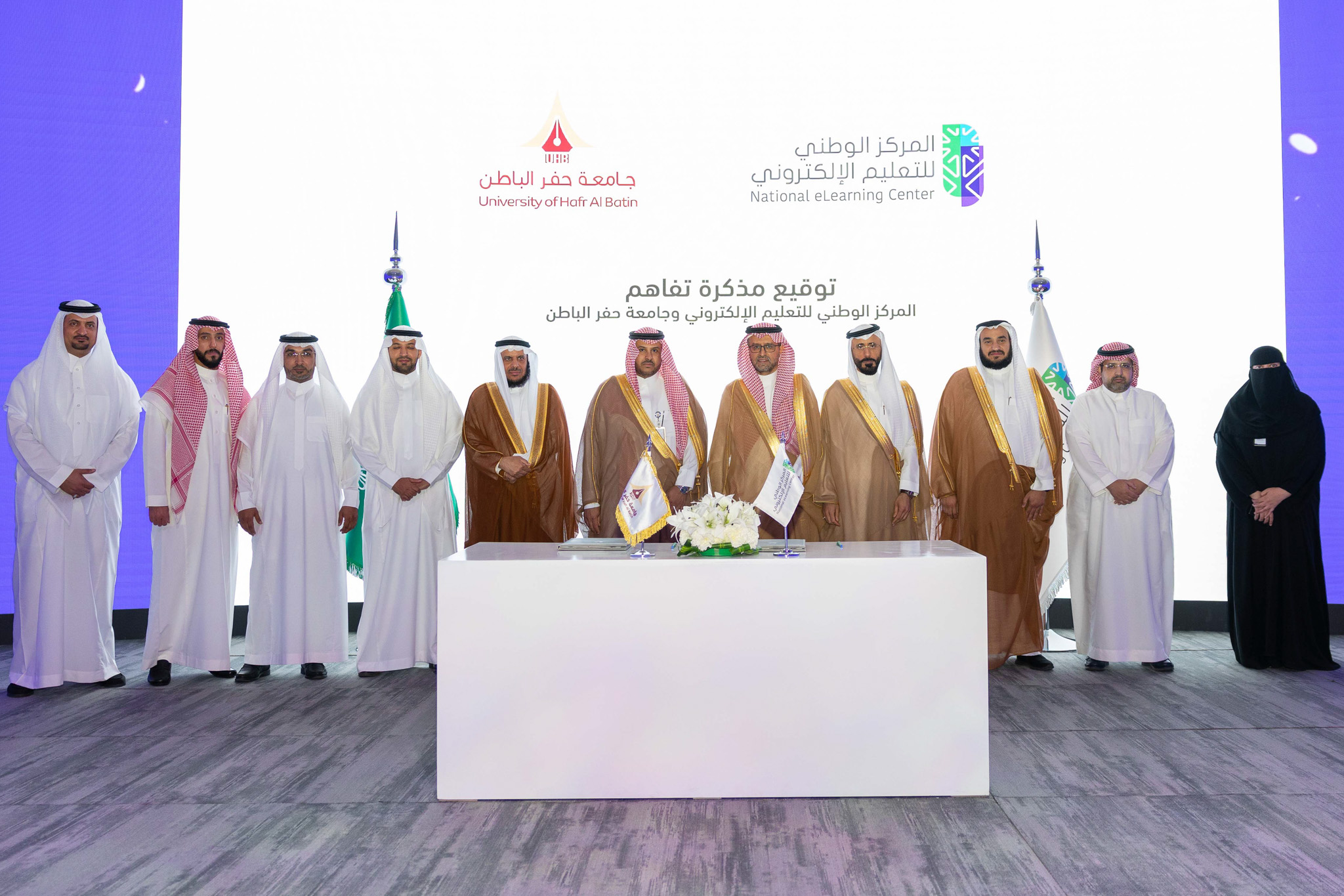 صورة من توقيع مذكرة تفاهم بين المركز الوطني للتعليم الإلكتروني وجامعة حفر الباطن، تعكس سعادة الدكتور عبدالله الوليدي، إلى جانب سعادة الدكتور خالد الحربي، و 8 رجال، وامرأة.