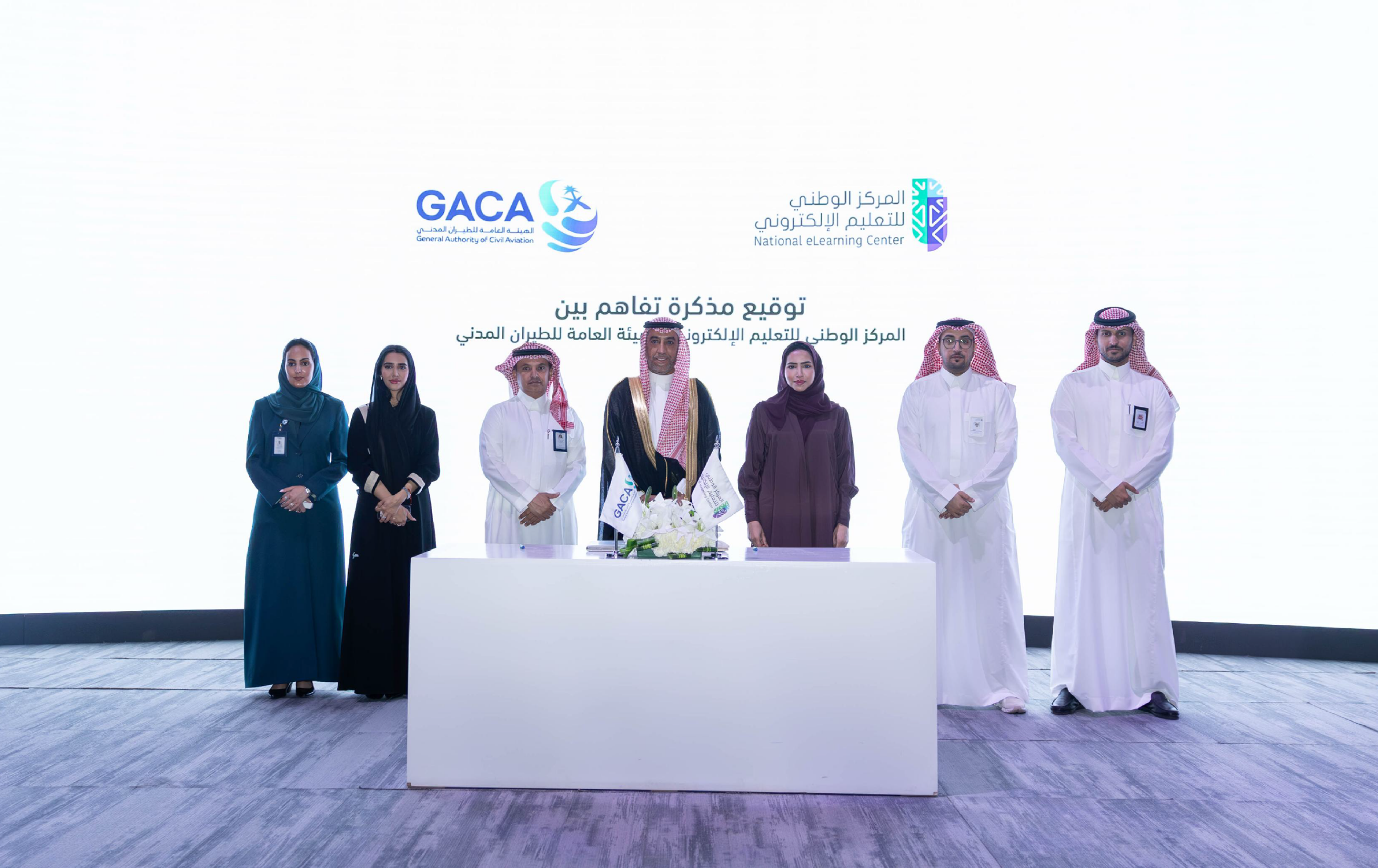 صورة لتوقيع مذكرة تفاهم بين المركز الوطني للتعليم الإلكتروني والهيئة العامة للطيران المدني، توضح سعادة الدكتورة هاجر بن عصفور، وسعادة الأستاذ محمد الفوزان، إلى جانب 3 رجال، وامرأتان.