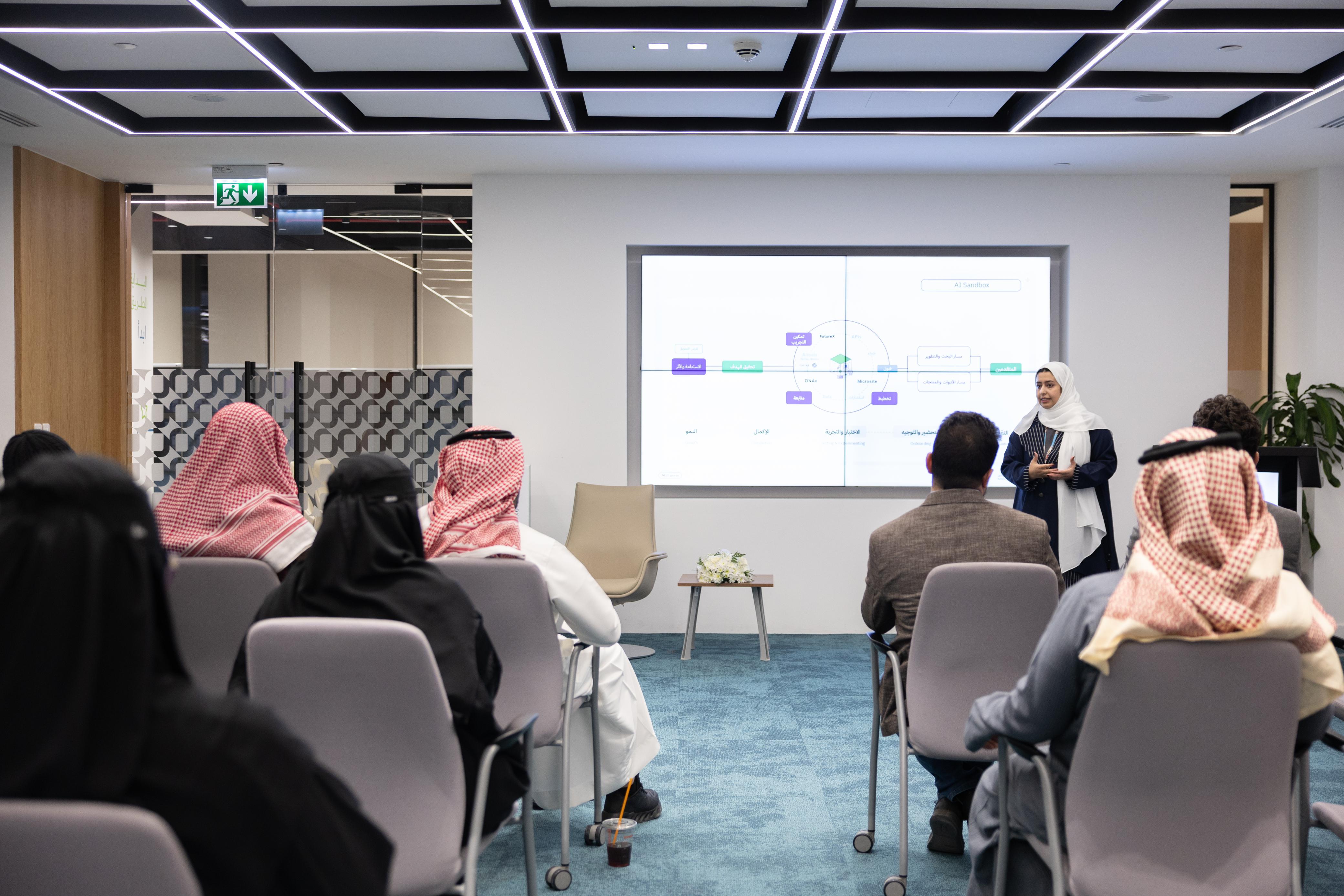 صورة من مشاركة المركز الوطني للتعليم الإلكتروني في أسبوع التعليم، حيث تعكس تقديم الأستاذة أمواج الزهراني للقاء تعريفي حول المركز، مقابل مجموعة من الحضور.