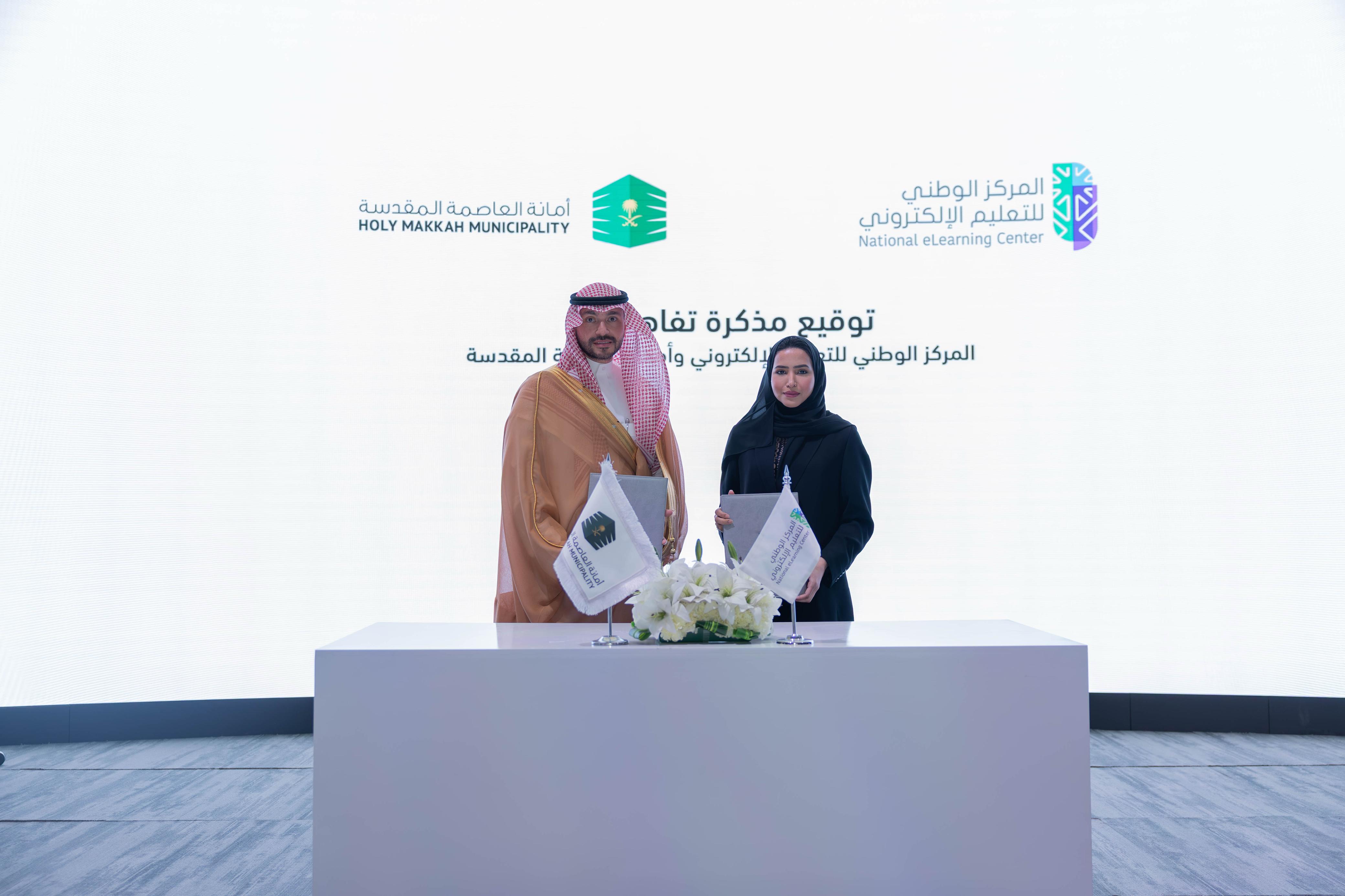 صورة لتوقيع مذكرة تفاهم بين المركز الوطني للتعليم الإلكتروني وأمانة العاصمة المقدسة، توضح الأستاذة هاجر بن عصفور، إلى جانب الأستاذ محمد عادل بخاري.