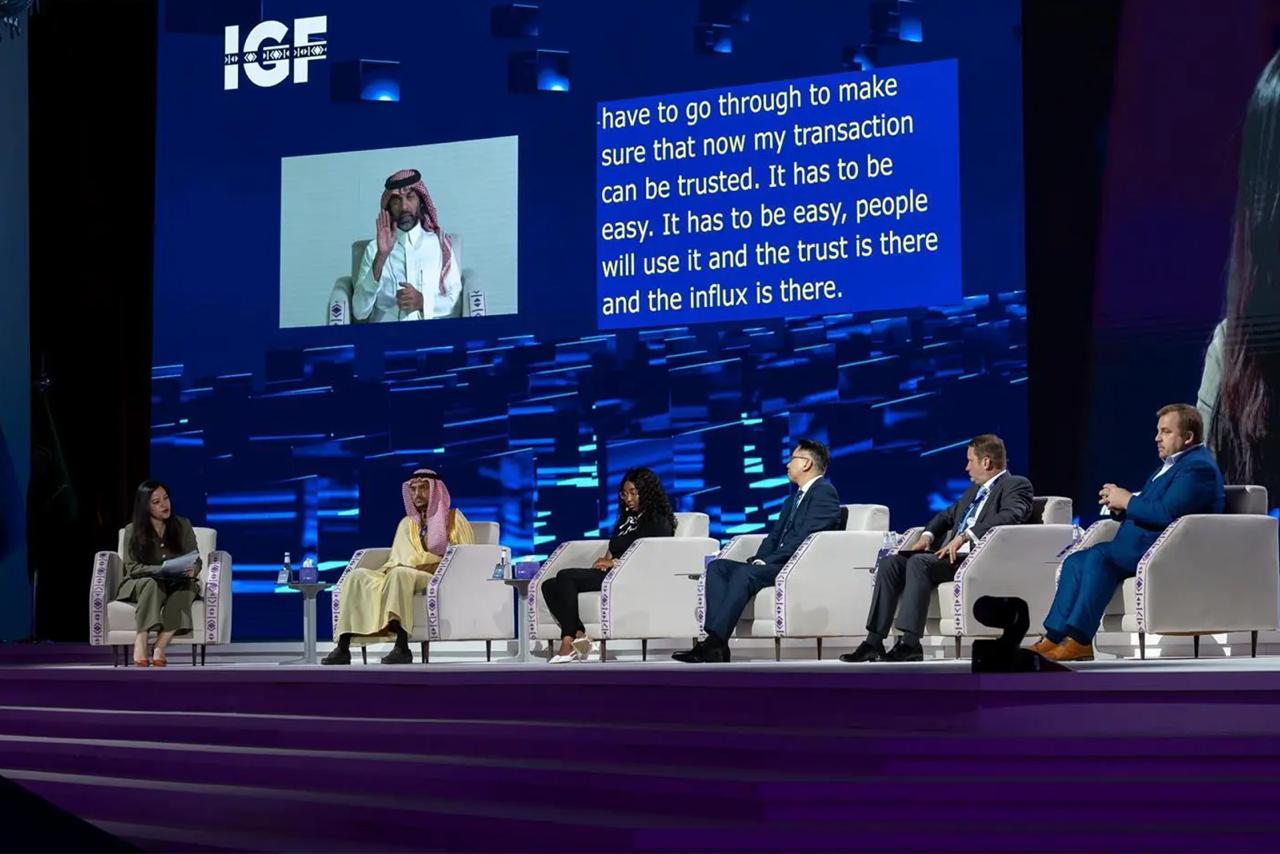 صورة لإعلان تحقيق المركز الوطني للتعليم الإلكتروني المركز الخامس ضمن أفضل الجهات الحكومية في قطاع التعليم والتدريب في المملكة، خلال افتتاح أعمال ملتقى الحكومة الرقمية، حيث تعكس الصورة 4 رجال، وامرأتان، إلى جانب شاشة زرقاء بالخلف يتوسطها رجل يرافقه نص.