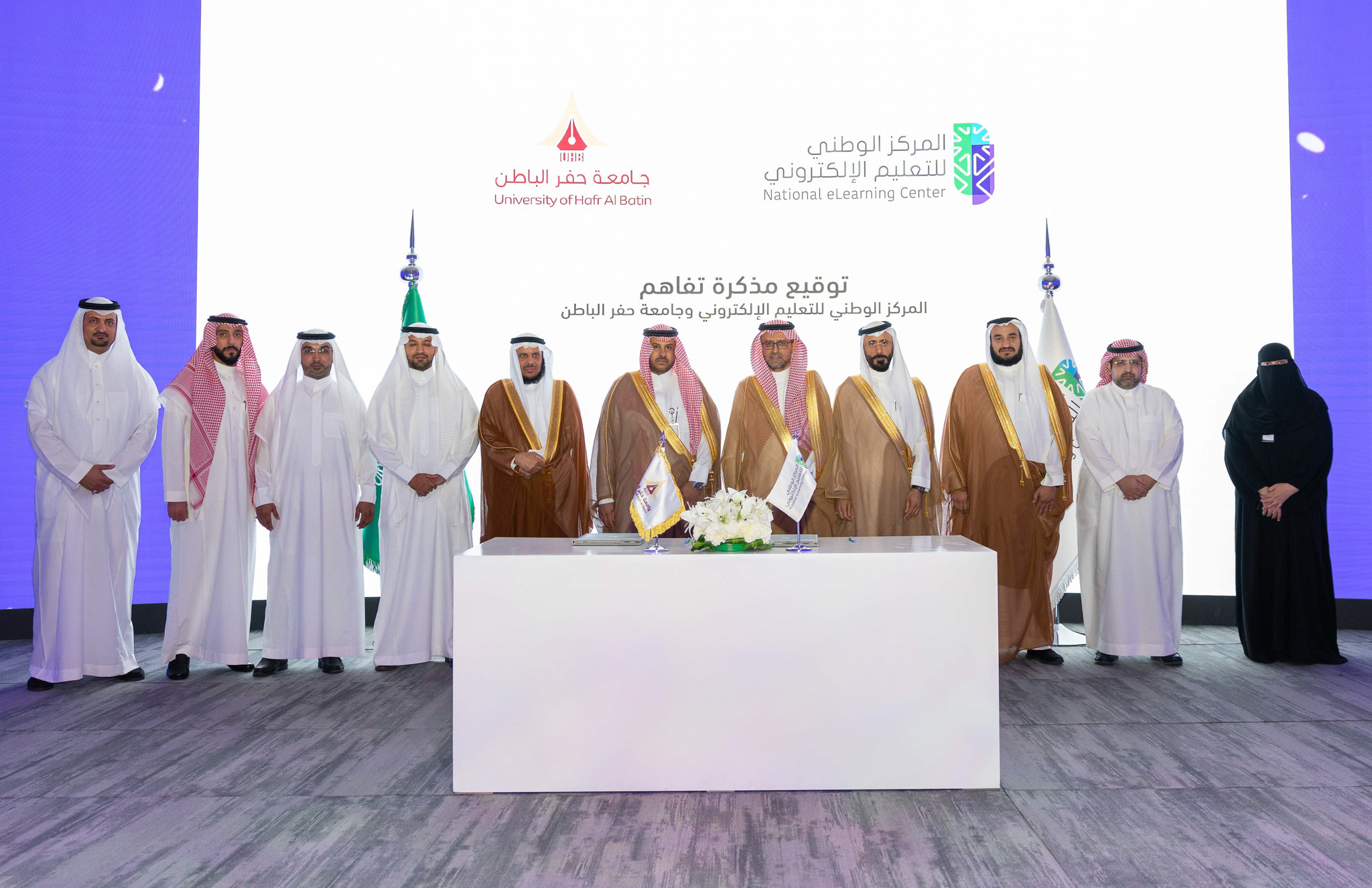 صورة من توقيع مذكرة تفاهم بين المركز الوطني للتعليم الإلكتروني وجامعة حفر الباطن، تعكس سعادة الدكتور عبدالله الوليدي، إلى جانب سعادة الدكتور خالد الحربي، و 8 رجال، وامرأة.