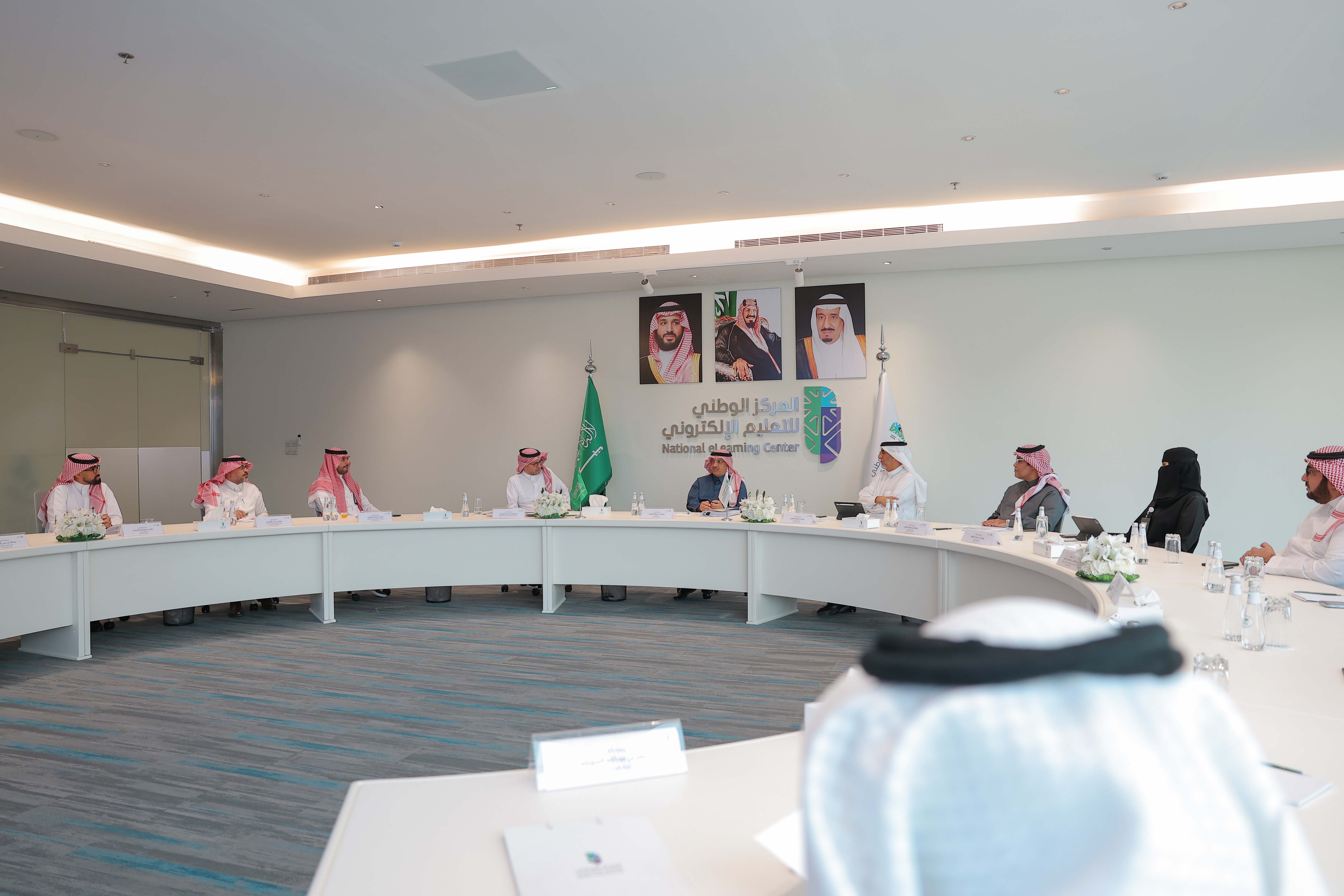 صور من اجتماع مجلس إدارة المركز الخامس عشر، تعكس معالي الأستاذ يوسف البنيان، الدكتور عبدالله الوليدي، الدكتور سعد القصبي، الدكتور صالح الغامدي، الدكتورة نورة المهنا، المهندس عبدالله الدخيل، المهندس أحمد الصويان، المهندس خالد المحيسن، بالإضافة إلى وجود شعار وعلم المركز، علم المملكة، صور لقادة المملكة في الخلف.