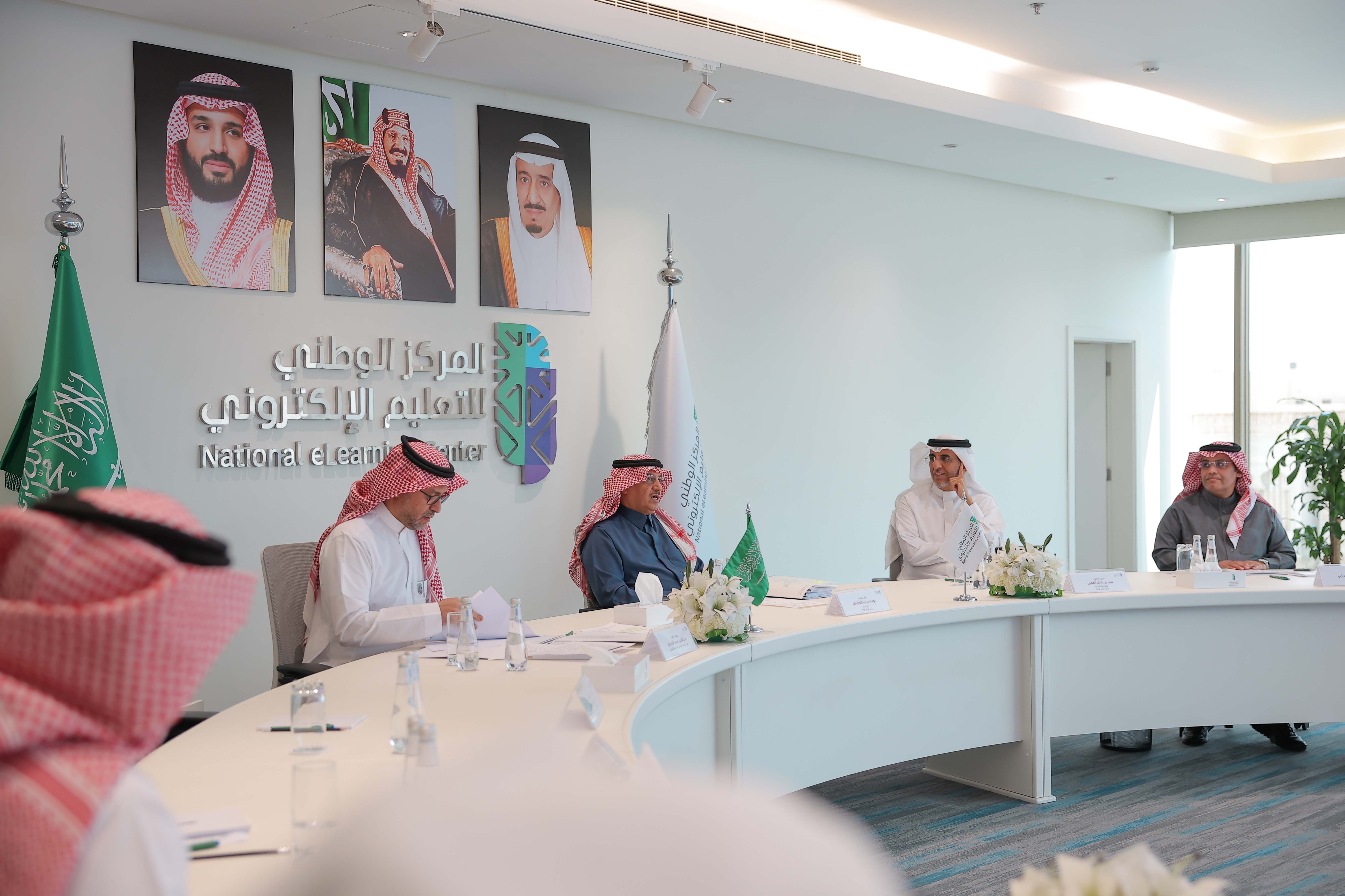 صور من اجتماع مجلس إدارة المركز الخامس عشر، تعكس معالي الأستاذ يوسف البنيان، الدكتور عبدالله الوليدي، الدكتور سعد القصبي، الدكتور صالح الغامدي، الدكتورة نورة المهنا، المهندس عبدالله الدخيل، المهندس أحمد الصويان، المهندس خالد المحيسن، بالإضافة إلى وجود شعار وعلم المركز، علم المملكة، صور لقادة المملكة في الخلف.