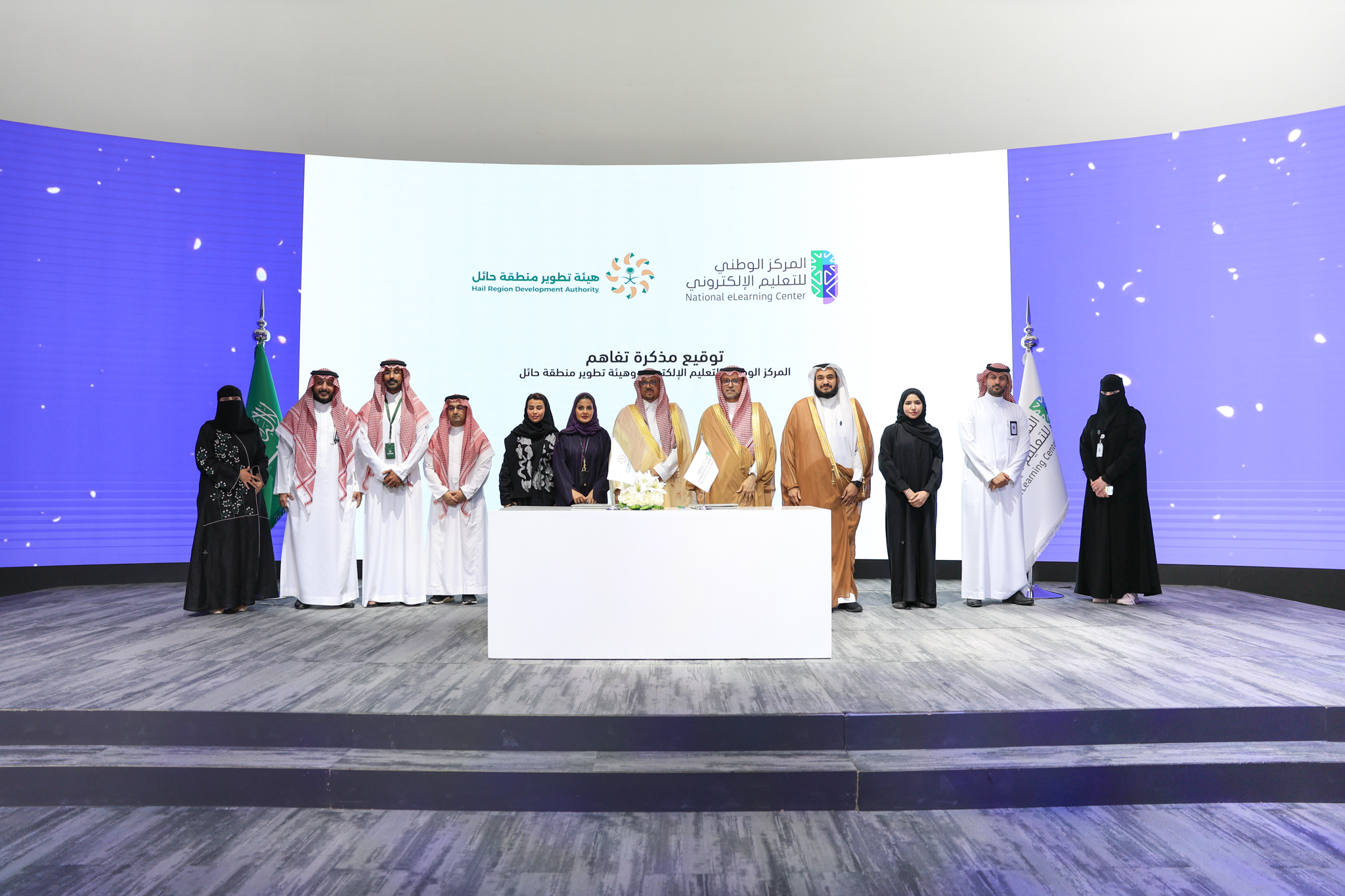 صورة من توقيع مذكرة تفاهم بين المركز الوطني للتعليم الإلكتروني وهيئة تطوير منطقة حائل، تعكس سعادة الدكتور عبدالله الوليدي، إلى جانب سعادة الأستاذ عمر بن عبدالجبار، و 5 رجال، و 5 نساء.